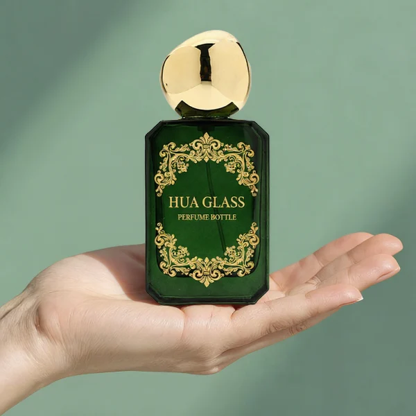 HUA0343 perfume bottle, rectangular semi-transparent blue, pink, amber, or smoky black glass body with beveled edges and thick base, 30 ml, 50 ml, or 100 ml liquid, glossy black spherical plastic cap with smooth polished surface, black bottle neck, gold printed brand logo on bottle surface, modern artistic luxury design, ideal for gifting and daily use.