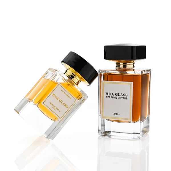 HUA0344 perfume bottle, rectangular transparent colorless glass body with beveled edges and thick base, 30 ml, 50 ml, or 100 ml liquid, wide glossy black cylindrical plastic cap with convex top and flat sides, gold screw-type bottle neck, brand logo label attached on bottle surface, modern minimalist luxury design, ideal for gifting and daily use.