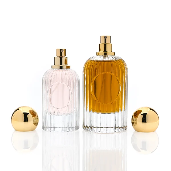 HUA0345 perfume bottle, cylindrical transparent colorless glass body with vertical ribbed texture, 50 ml or 100 ml liquid, spherical glossy gold plastic cap with magnetic closure, gold bottle neck, gold aluminum label attached on bottle surface, elegant luxury design, ideal for gifting and daily use.