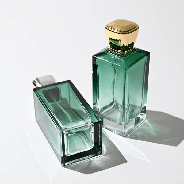 HUA0346 perfume bottle, rectangular transparent colorless glass body with gradient blue, green, or amber tint, 100 ml liquid, glossy square plastic cap with smooth curved sides, no bottle neck, gold printed brand logo on bottle surface, modern luxury minimalist design, ideal for gifting and daily use.