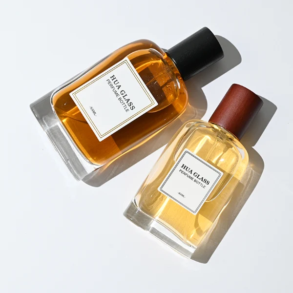 HUA0353 perfume bottle, flat cylindrical glass body with reddish-brown or black cylindrical wooden cap, square paper label with minimalist border, Nordic minimalist fragrance packaging design available in 50ml and 75ml