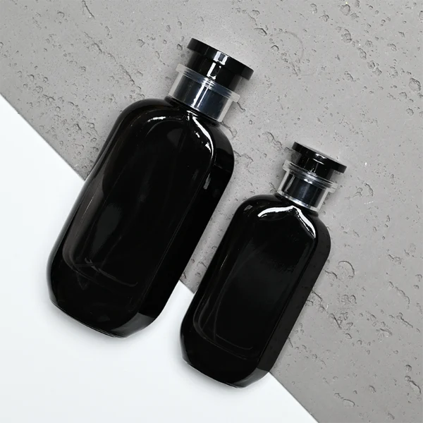 HUA0354 perfume bottle, cylindrical glass body in black, green, and blue with vertical gold printed logo, black plastic cap with a transparent accent ring, modern bold luxury fragrance packaging design available in 50ml and 100ml