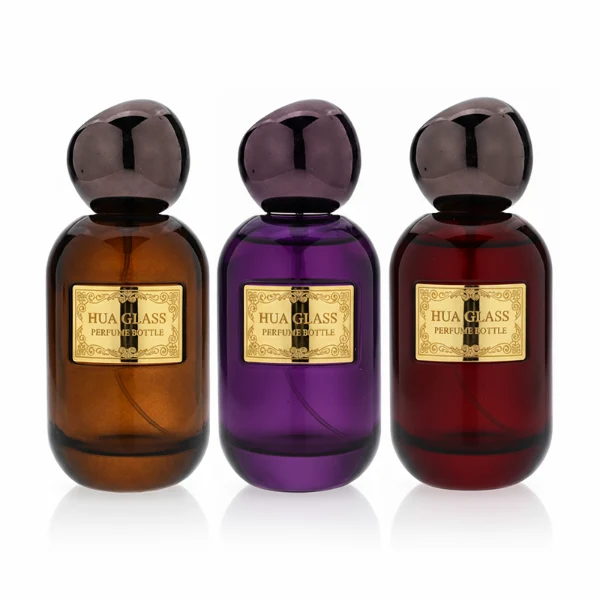 HUA0355 perfume bottle, colored cylindrical glass body in amber brown, purple, and burgundy red with gold aluminum label plate, irregular sculptural pebble plastic cap, luxury artistic vintage fragrance packaging design