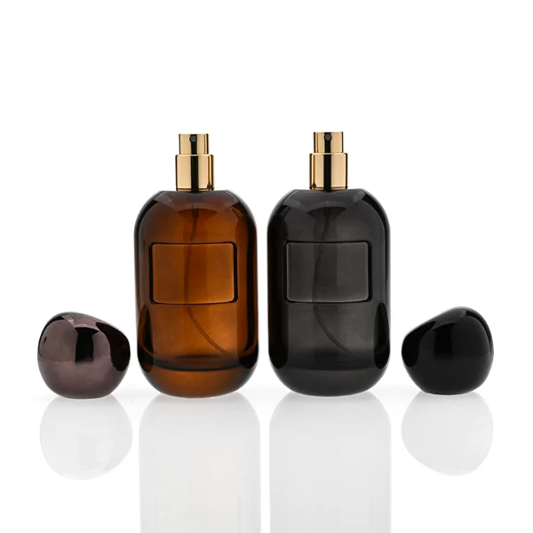 HUA0355 perfume bottle, colored cylindrical glass body in amber brown, purple, and burgundy red with gold aluminum label plate, irregular sculptural pebble plastic cap, luxury artistic vintage fragrance packaging design