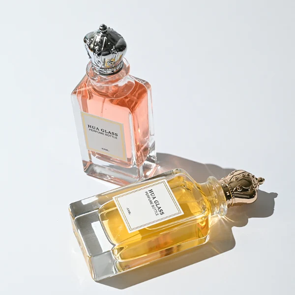 HUA0356 perfume bottle, rectangular cuboid clear glass body with ornate engraved gold or silver royal crown cap, centered paper label with elegant border, luxury imperial vintage fragrance packaging design