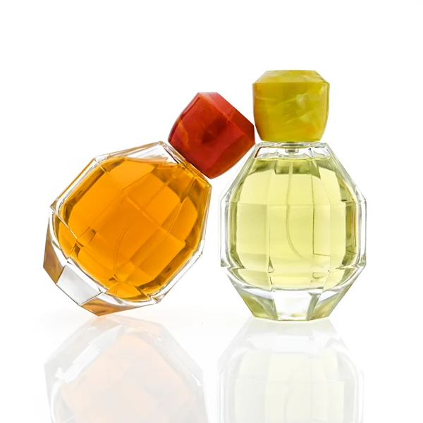 HUA0357 perfume bottle, multi-faceted geometric cut spherical clear glass body with orange-red or yellow marble-textured resin cap, centered square minimalist paper label, contemporary artistic luxury fragrance packaging design