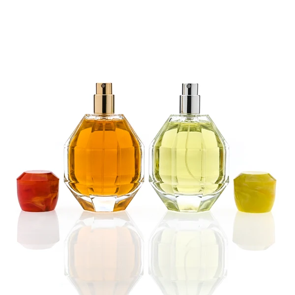 HUA0357 perfume bottle, multi-faceted geometric cut spherical clear glass body with orange-red or yellow marble-textured resin cap, centered square minimalist paper label, contemporary artistic luxury fragrance packaging design