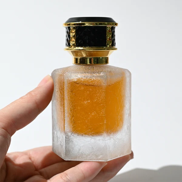 HUA0358 perfume bottle, hexahedral column glass body in translucent blue, pink, and purple with gold neck and gold printed logo, black mesh-textured plastic cap, chic contemporary fragrance packaging design available in 50ml and 100ml