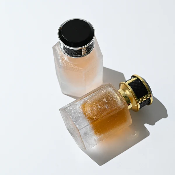 HUA0358 perfume bottle, hexahedral column glass body in translucent blue, pink, and purple with gold neck and gold printed logo, black mesh-textured plastic cap, chic contemporary fragrance packaging design available in 50ml and 100ml