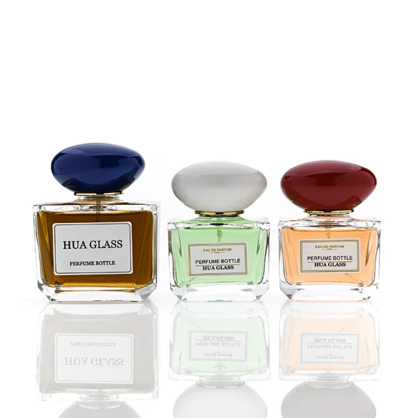 HUA0359 perfume bottle, low rectangular clear glass body with gold neck and a paper label attached, smooth oval pebble plastic cap in navy blue, white, or burgundy, contemporary artistic luxury fragrance packaging design available in 50ml and 100ml
