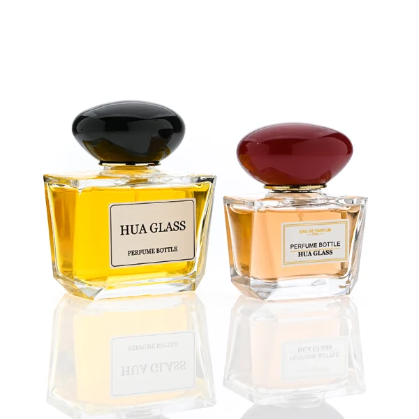 HUA0359 perfume bottle, low rectangular clear glass body with gold neck and a paper label attached, smooth oval pebble plastic cap in navy blue, white, or burgundy, contemporary artistic luxury fragrance packaging design available in 50ml and 100ml