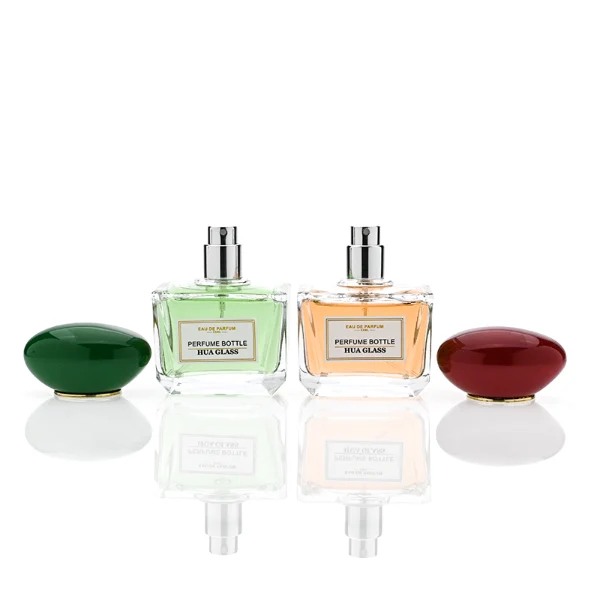 HUA0359 perfume bottle, low rectangular clear glass body with gold neck and a paper label attached, smooth oval pebble plastic cap in navy blue, white, or burgundy, contemporary artistic luxury fragrance packaging design available in 50ml and 100ml
