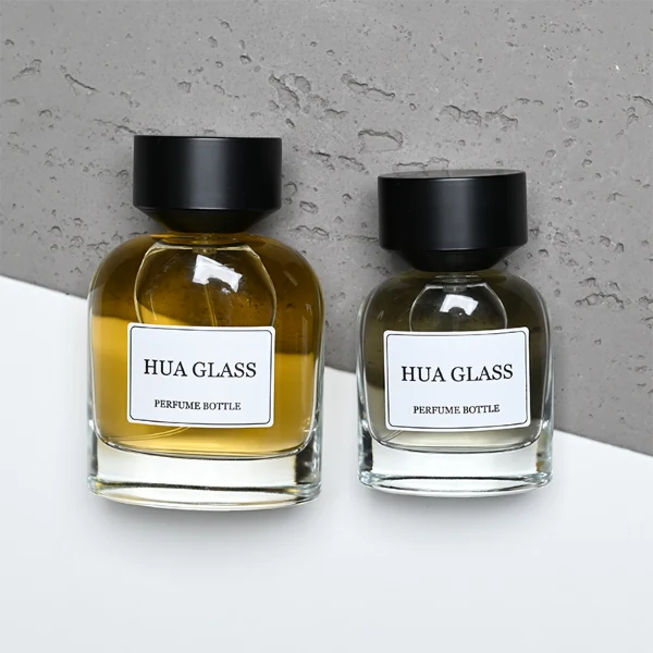 HUA0361 perfume bottle, round cylindrical clear glass body with a paper label attached, matte black inverted cone plastic cap, contemporary minimalist luxury fragrance packaging design available in 50ml and 100ml