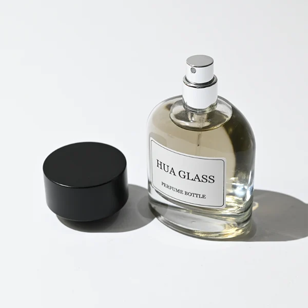 HUA0361 perfume bottle, round cylindrical clear glass body with a paper label attached, matte black inverted cone plastic cap, contemporary minimalist luxury fragrance packaging design available in 50ml and 100ml