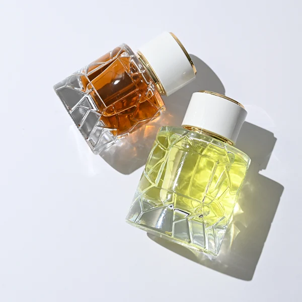 HUA0362 perfume bottle, textured ice-crack cylindrical clear glass body with gold neck and gold aluminum label, straight cylindrical white plastic cap with luxury gold trim, modern artistic luxury fragrance packaging design available in 50ml and 100ml