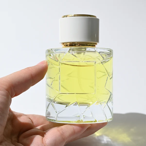 HUA0362 perfume bottle, textured ice-crack cylindrical clear glass body with gold neck and gold aluminum label, straight cylindrical white plastic cap with luxury gold trim, modern artistic luxury fragrance packaging design available in 50ml and 100ml