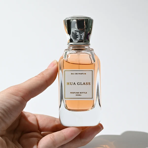 HUA0363 perfume bottle, flat rectangular clear glass body with centered paper label, elegant trophy-shaped plastic cap in gold or silver finish, royal classic luxury fragrance packaging design available in 50ml and 100ml