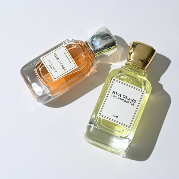 HUA0363 perfume bottle, flat rectangular clear glass body with centered paper label, elegant trophy-shaped plastic cap in gold or silver finish, royal classic luxury fragrance packaging design available in 50ml and 100ml
