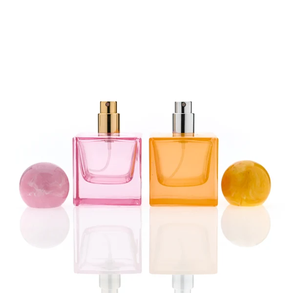 HUA0367 perfume bottle, square cubic glass body in translucent pink or amber orange with gold printed logo, oversized spherical ball plastic cap with marble veins texture, contemporary artistic pop luxury fragrance packaging design available in 30ml, 50ml, and 100ml