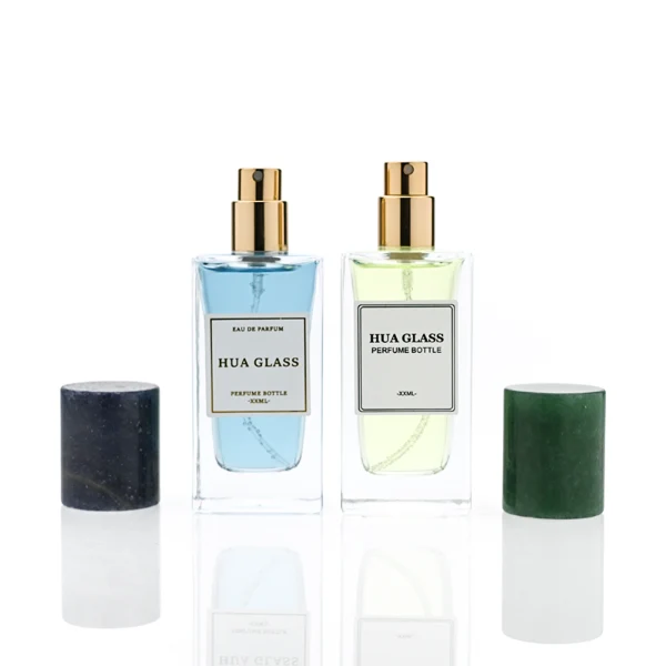 HUA0369 perfume bottle, rectangular cuboid clear glass body with centered paper label, premium cylindrical natural marble cap in white veined, jade green, and dark blue stone textures with gold or silver neck, Nordic minimalist luxury fragrance packaging design available in 30ml, 50ml, and 100ml