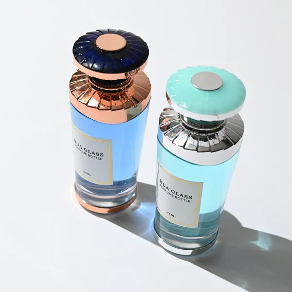HUA0371 perfume bottle, inverted tapered glass body in translucent green or blue with centered paper label, ribbed umbrella-shaped plastic cap in mint green with silver or shiny black with rose gold wave shoulder accents, avant-garde luxury fragrance packaging design available in 50ml and 100ml