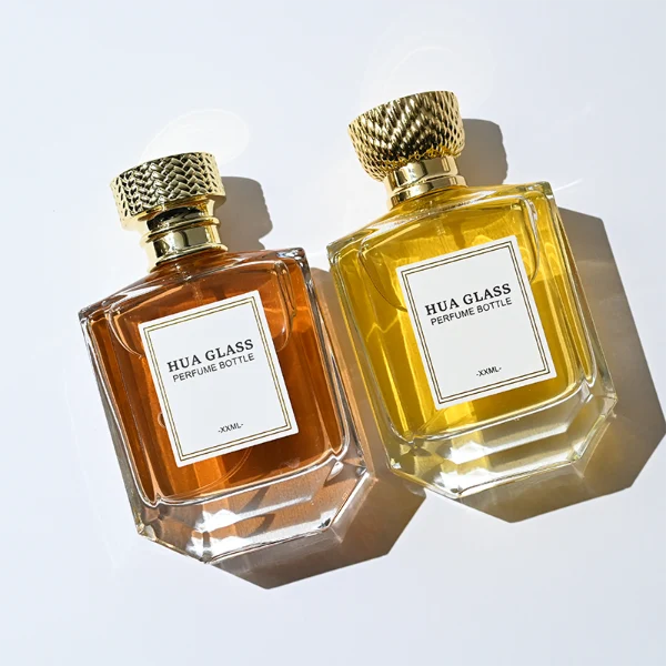 HUA0374 perfume bottle, flat hexagonal multi-faceted clear glass body with gold neck and centered paper label, textured inverted trapezoid gold plastic cap in grid knurled or chevron ribbed patterns matching the gold neck, Art Deco luxury fragrance packaging design in 100ml