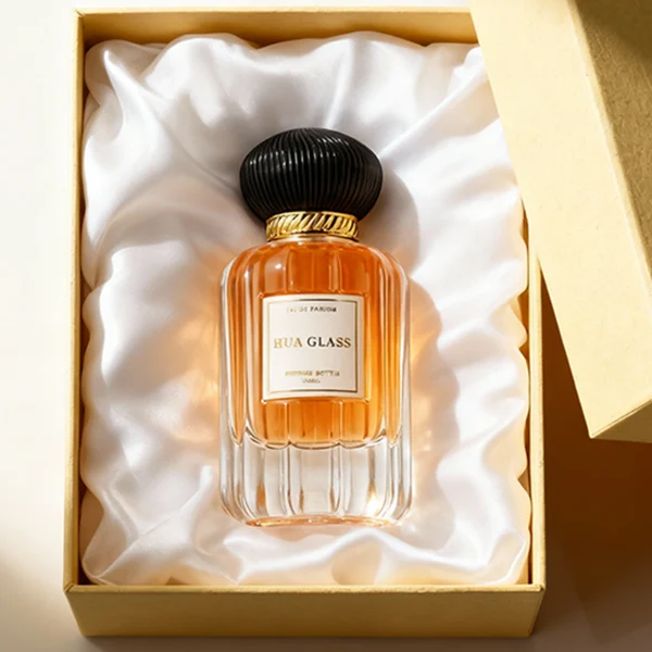 HUA0376 perfume bottle, vertical fluted clear glass body with diagonal twisted gold neck and centered paper label, swirling textured pumpkin-shaped plastic cap in shiny gold with black lines or matte white, neoclassical luxury fragrance packaging design available in 50ml and 100ml