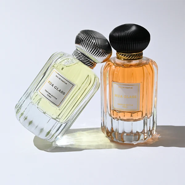 HUA0376 perfume bottle, vertical fluted clear glass body with diagonal twisted gold neck and centered paper label, swirling textured pumpkin-shaped plastic cap in shiny gold with black lines or matte white, neoclassical luxury fragrance packaging design available in 50ml and 100ml