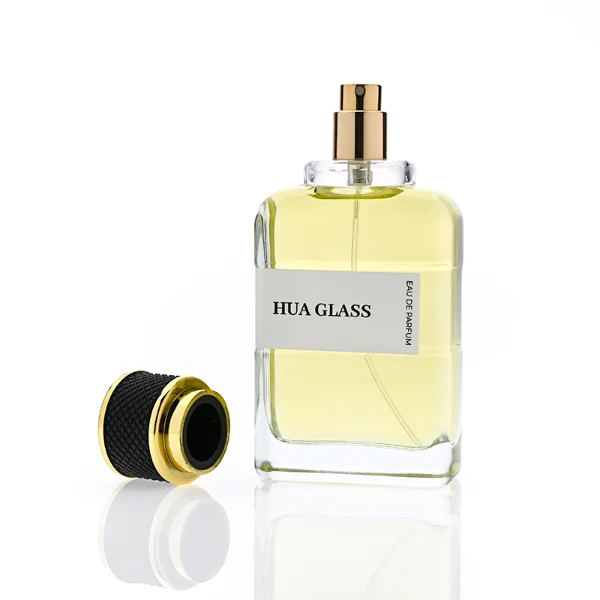 HUA0377 perfume bottle, flat rectangular cuboid clear glass body with gold neck and wrapped paper label, textured diamond knurled cylindrical plastic cap with gold trim in dark brown or black, modern industrial luxury fragrance packaging design in 100ml