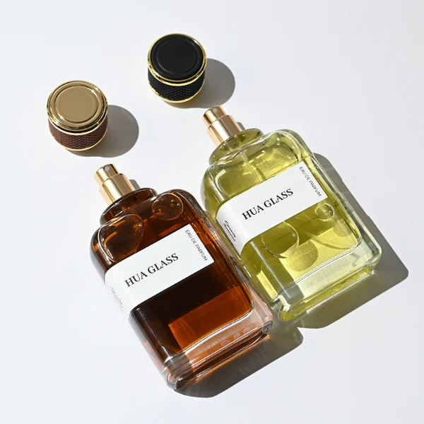 HUA0377 perfume bottle, flat rectangular cuboid clear glass body with gold neck and wrapped paper label, textured diamond knurled cylindrical plastic cap with gold trim in dark brown or black, modern industrial luxury fragrance packaging design in 100ml