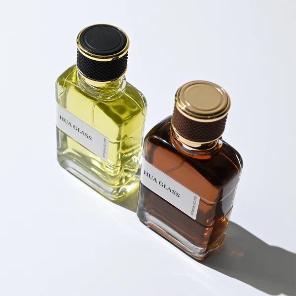 HUA0377 perfume bottle, flat rectangular cuboid clear glass body with gold neck and wrapped paper label, textured diamond knurled cylindrical plastic cap with gold trim in dark brown or black, modern industrial luxury fragrance packaging design in 100ml