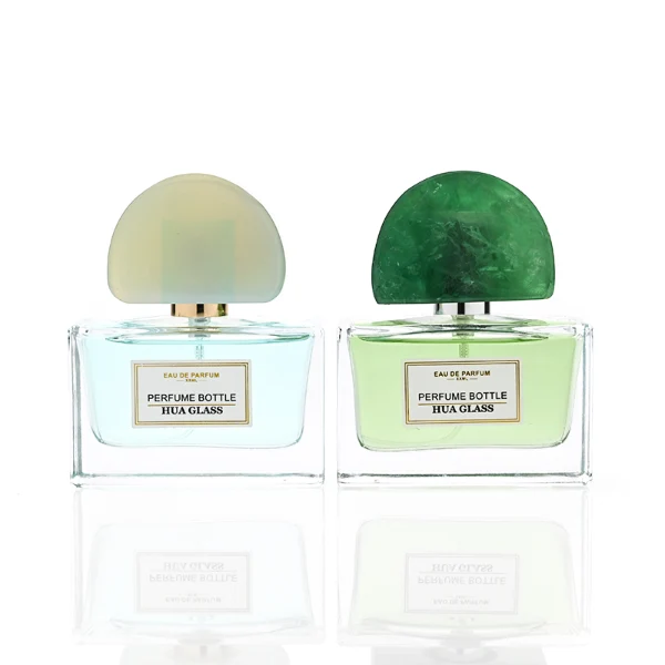 HUA0378 perfume bottle, wide rectangular cuboid clear glass body with gold or silver neck and centered paper label, unique semi-circular arch semi-precious stone cap in translucent pale quartz or rich deep green mineral textures, architectural luxury fragrance packaging design available in 30ml, 50ml, and 100ml