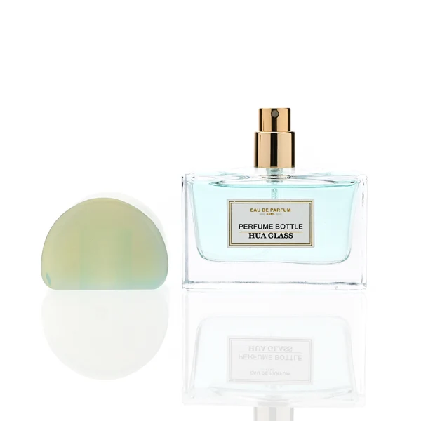 HUA0378 perfume bottle, wide rectangular cuboid clear glass body with gold or silver neck and centered paper label, unique semi-circular arch semi-precious stone cap in translucent pale quartz or rich deep green mineral textures, architectural luxury fragrance packaging design available in 30ml, 50ml, and 100ml