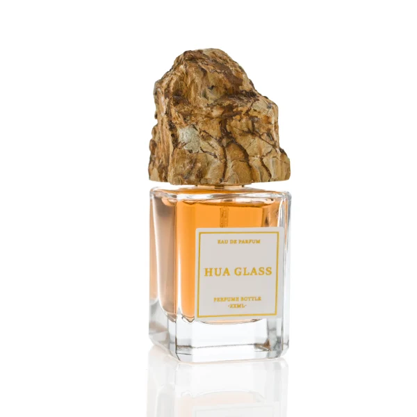 HUA0379 perfume bottle, cylindrical clear glass body with centered paper label, rugged organic raw semi-precious stone cap in pink rose quartz, tiger's eye jasper, green bloodstone or black lava rock textures, artistic luxury fragrance packaging design available in 30ml, 50ml, and 100ml