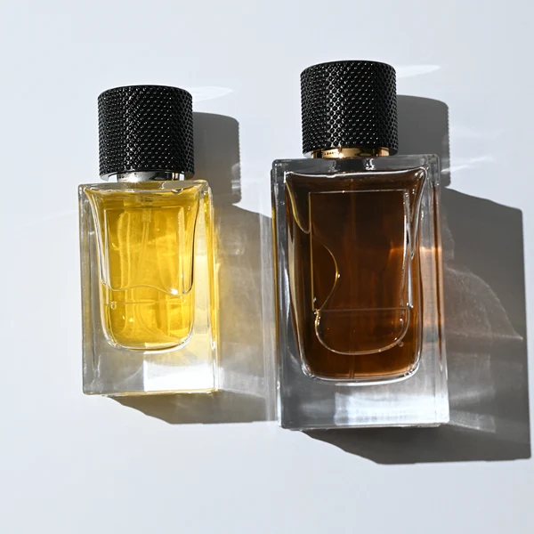 HUA0382 perfume bottle, square cubic clear glass body with architectural vertical fluting flutes, shiny gold neck and centered gold rectangular label, diamond knurled cylindrical plastic cap in deep brown or black matte finishes, luxury niche fragrance packaging design available in 50ml and 100ml