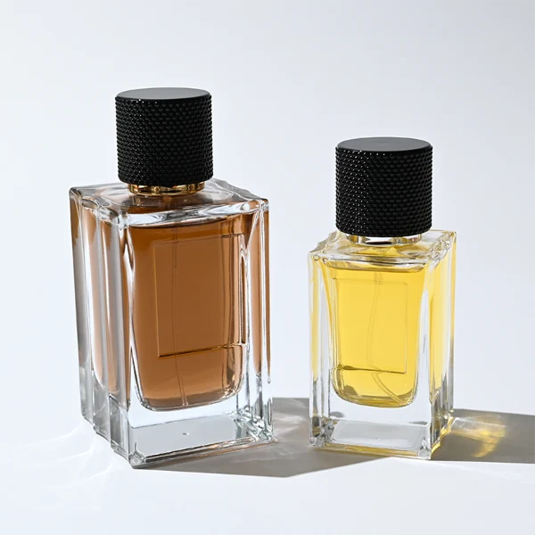 HUA0382 perfume bottle, square cubic clear glass body with architectural vertical fluting flutes, shiny gold neck and centered gold rectangular label, diamond knurled cylindrical plastic cap in deep brown or black matte finishes, luxury niche fragrance packaging design available in 50ml and 100ml