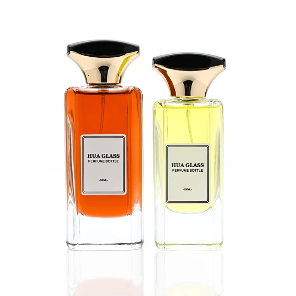 HUA0384 perfume bottle, flat rectangular cuboid clear glass body with beveled edges and centered paper label, unique dual-tone funnel-shaped plastic cap with glossy black top and gold body, luxury fragrance packaging design available in 50ml and 100ml