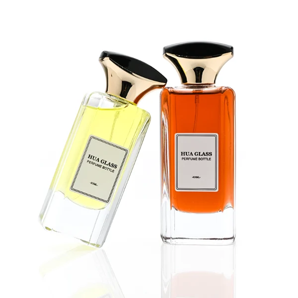 HUA0384 perfume bottle, flat rectangular cuboid clear glass body with beveled edges and centered paper label, unique dual-tone funnel-shaped plastic cap with glossy black top and gold body, luxury fragrance packaging design available in 50ml and 100ml