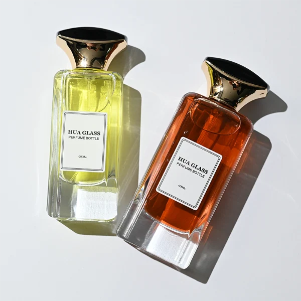 HUA0384 perfume bottle, flat rectangular cuboid clear glass body with beveled edges and centered paper label, unique dual-tone funnel-shaped plastic cap with glossy black top and gold body, luxury fragrance packaging design available in 50ml and 100ml