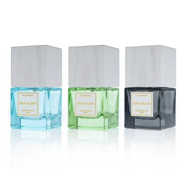 HUA0385 perfume bottle, square cubic clear glass body with heavy bottom and centered paper label, tall block cubic wooden cap showing organic wood grain textures in charcoal black or light grey-white, modern minimalist luxury fragrance packaging design available in 30ml, 50ml, and 100ml