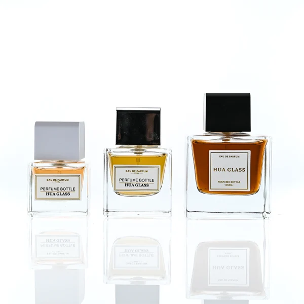 HUA0386 perfume bottle, flat rectangular cuboid clear glass body with heavy bottom and centered paper label, square cubic magnetic plastic cap in matte silver-grey or glossy black finishes, premium magnetic closure fragrance packaging design available in 30ml, 50ml, and 100ml