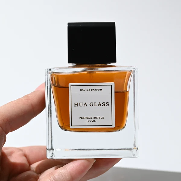 HUA0386 perfume bottle, flat rectangular cuboid clear glass body with heavy bottom and centered paper label, square cubic magnetic plastic cap in matte silver-grey or glossy black finishes, premium magnetic closure fragrance packaging design available in 30ml, 50ml, and 100ml
