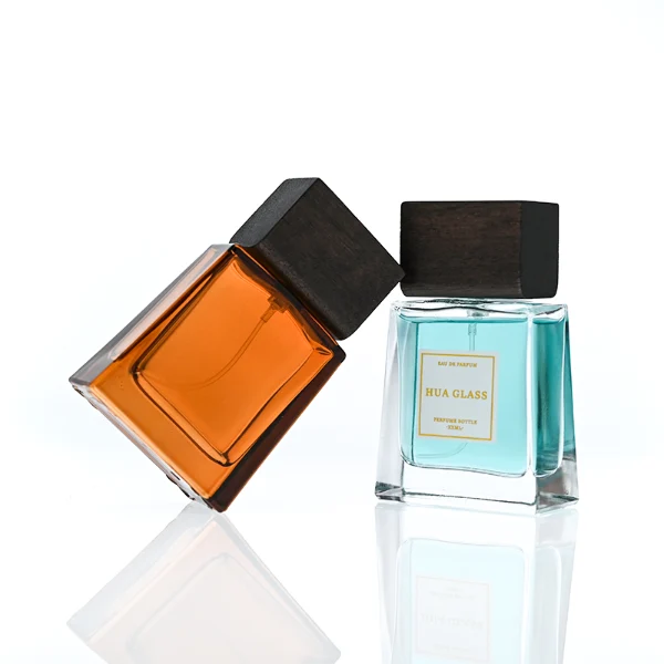 HUA0388 perfume bottle, flat trapezoidal clear glass body with heavy bottom and centered paper label, flat rectangular block wooden cap showing organic dark wood grain textures, luxury minimalist fragrance packaging design available in 50ml and 100ml