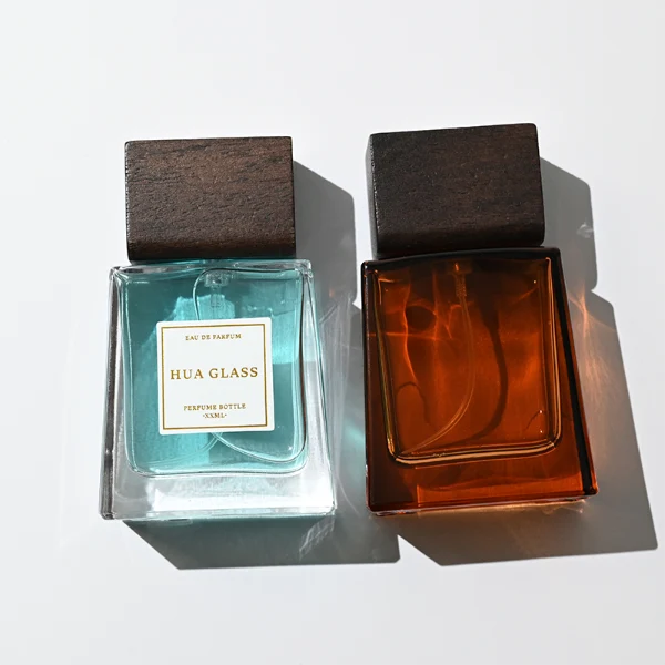 HUA0388 perfume bottle, flat trapezoidal clear glass body with heavy bottom and centered paper label, flat rectangular block wooden cap showing organic dark wood grain textures, luxury minimalist fragrance packaging design available in 50ml and 100ml