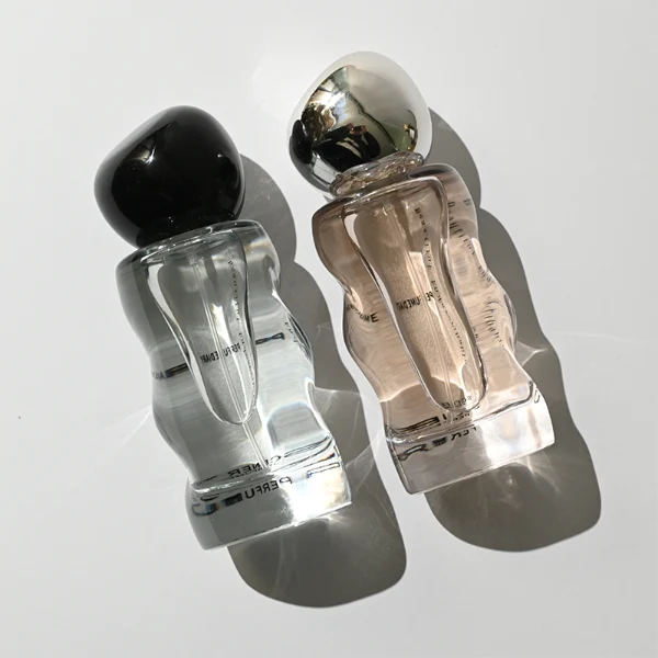 HUA0389 perfume bottle, wavy contoured cylindrical translucent colored glass body with centered gold brand logo and text, sleek spherical dome plastic cap in shiny silver chrome, avant-garde luxury fragrance packaging design in 50ml