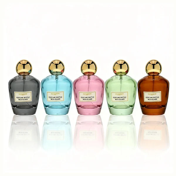 HUA0390 perfume bottle, rounded tapered clear glass body with heavy bottom and centered paper label, sleek spherical dome plastic cap in shiny gold or silver chrome finish, modern luxury fragrance packaging design in 100ml