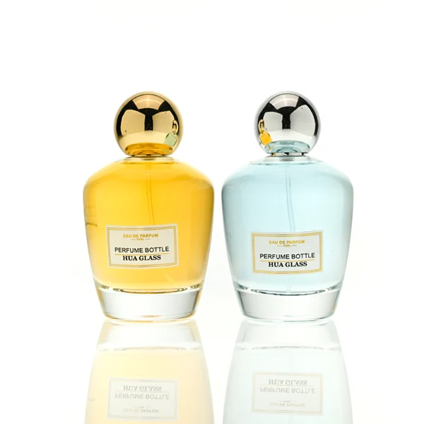 HUA0390 perfume bottle, rounded tapered clear glass body with heavy bottom and centered paper label, sleek spherical dome plastic cap in shiny gold or silver chrome finish, modern luxury fragrance packaging design in 100ml