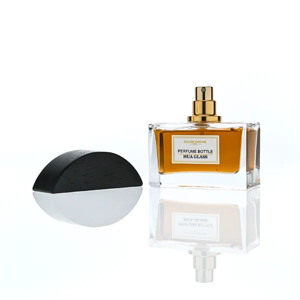 HUA0400 perfume bottle, flat rectangular cuboid glass body in transparent clear or translucent smoky black with heavy bottom and centered paper label, unique semi-circular arch-shaped wooden cap in matte black texture with shiny gold neck, modern luxury fragrance packaging design available in 30ml, 50ml, and 100ml
