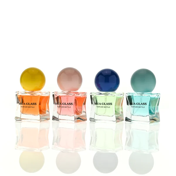 HUA0403 perfume bottle, compact cubic square glass body with translucent coating in blue, pink, black, green or brown and centered printed black brand logo, sleek spherical dome plastic cap in shiny gold finish, modern luxury fragrance packaging design in 15ml