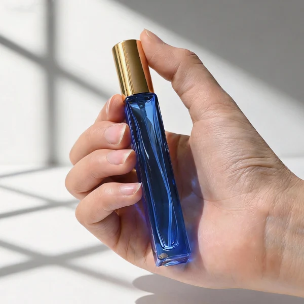 HUA0406 perfume bottle, slim cylindrical glass travel atomizer with transparent multi-color glass body in green, blue, red or yellow, featuring a luxury gold cylindrical zamak cap, modern minimalist travel fragrance packaging design available in 10ml